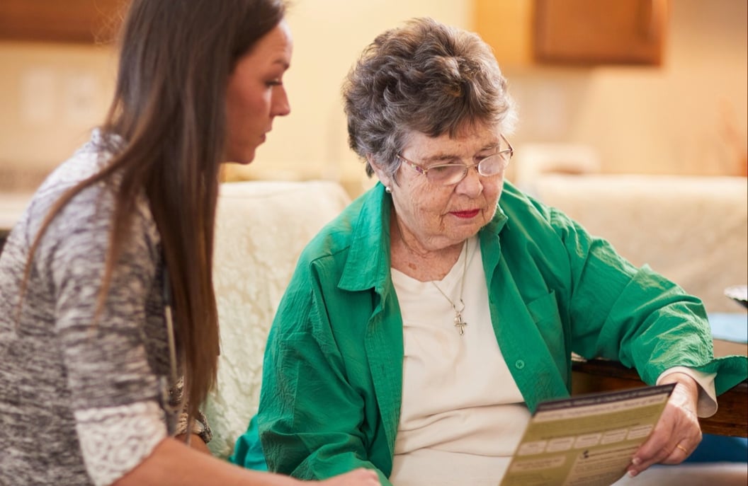 senior and worker looking at a book together