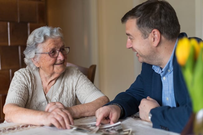 senior with adult son at a table looking at photos