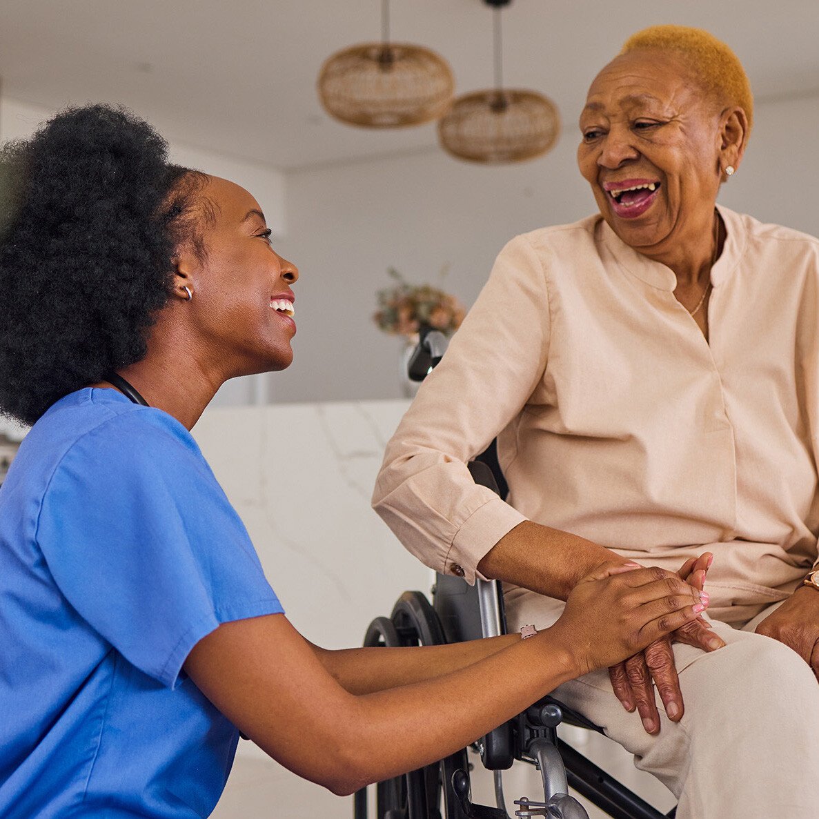 Senior woman in a wheelchair holding hands and smiling with caregiver