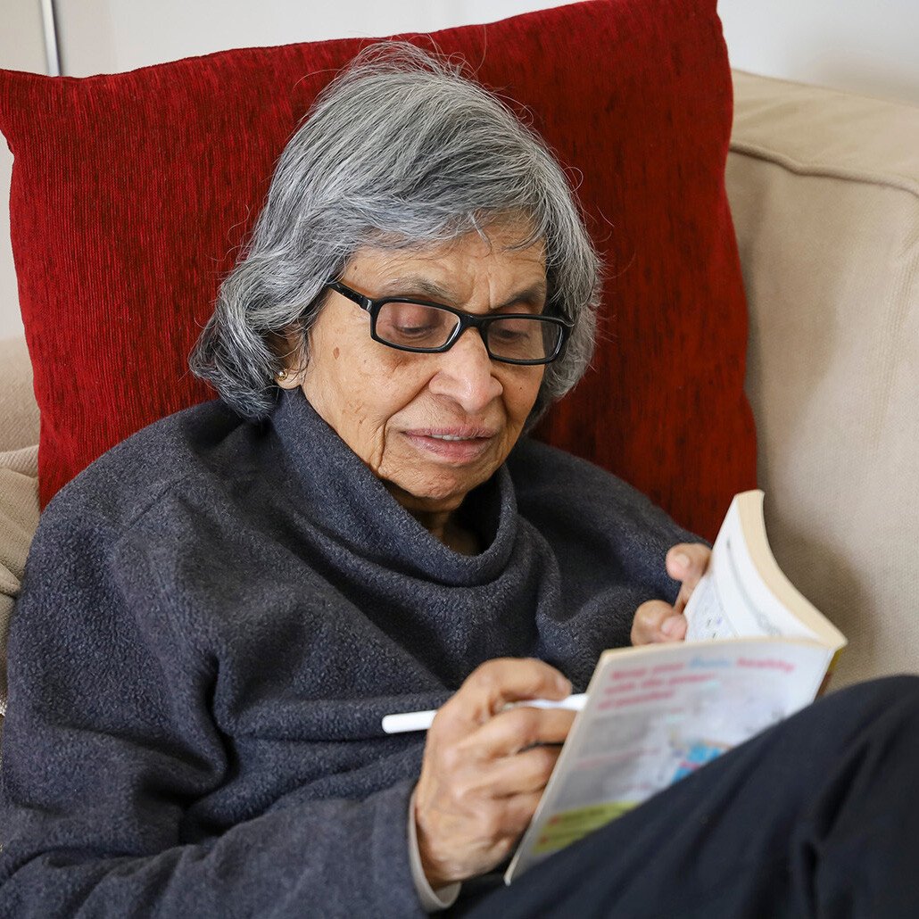 Senior woman writing in a notebook while sitting on couch