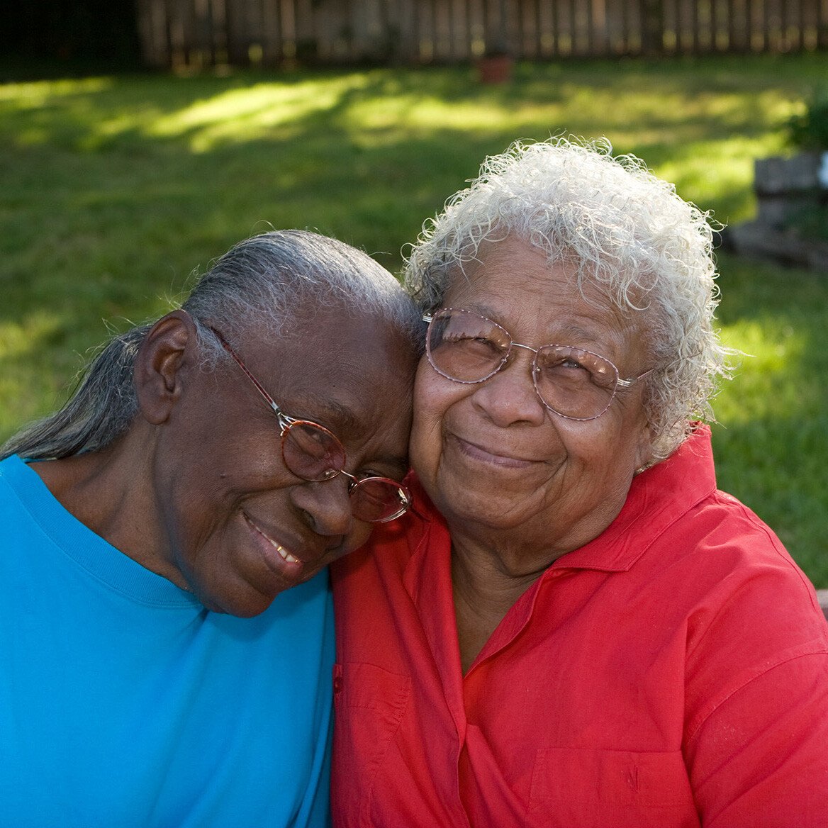 Two senior woman smiling and embracing outdoors