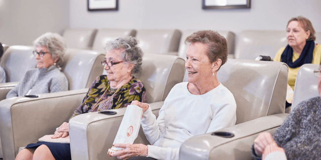 Senior friends enjoy a show in an assisted living theater