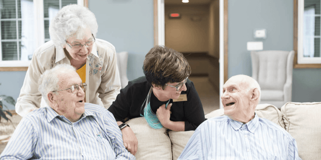 A Cedarhurst independent living team member chats with three residents on a couch