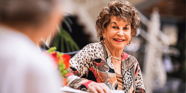 Two resident women smiling at a table together