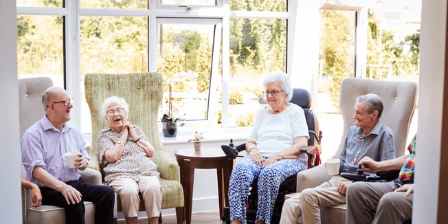 A group of senior assisted living residents enjoying coffee and conversation. 