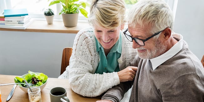 Senior couple enjoying retirement living as they sit at a kitchen table together