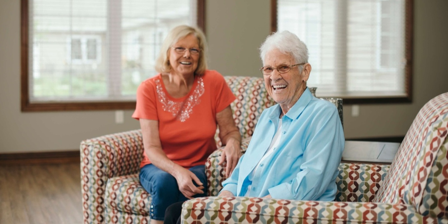 Seniors sitting on a couch and smiling at the camera