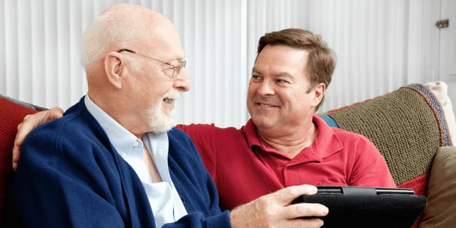 Son helping his father find a memory care facility on a tablet.