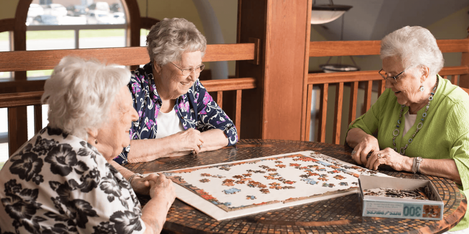 Senior women putting together a puzzle in memory care senior living community