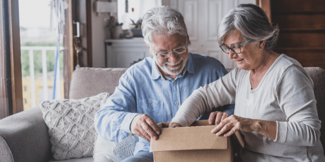 An older couple packing boxes to move into a senior living community. 