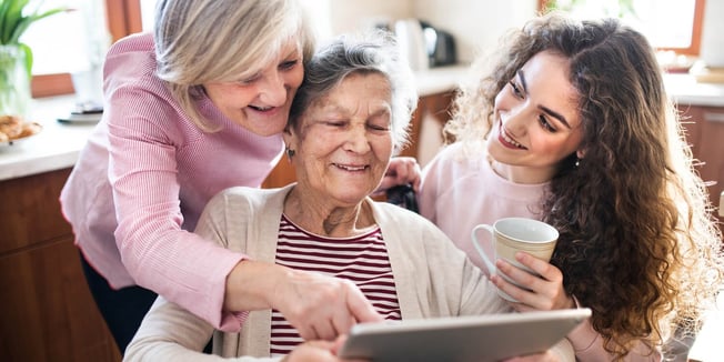 Multi-generational family looking at tablet screen while researching the cost of senior living.