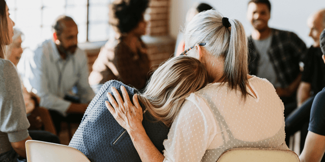 Women caregivers embracing during a senior caregiver support group