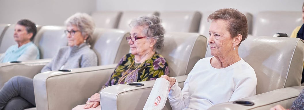 senior women eating popcorn and watching movie in movie theatre