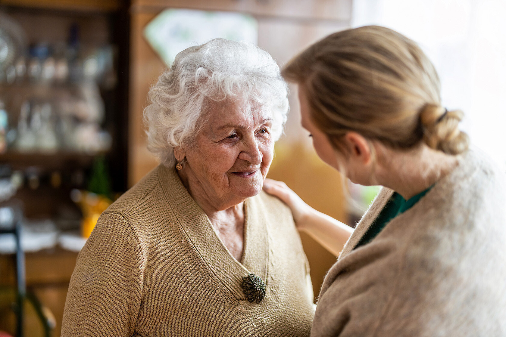 Senior caregiver talking to senior woman with dementia