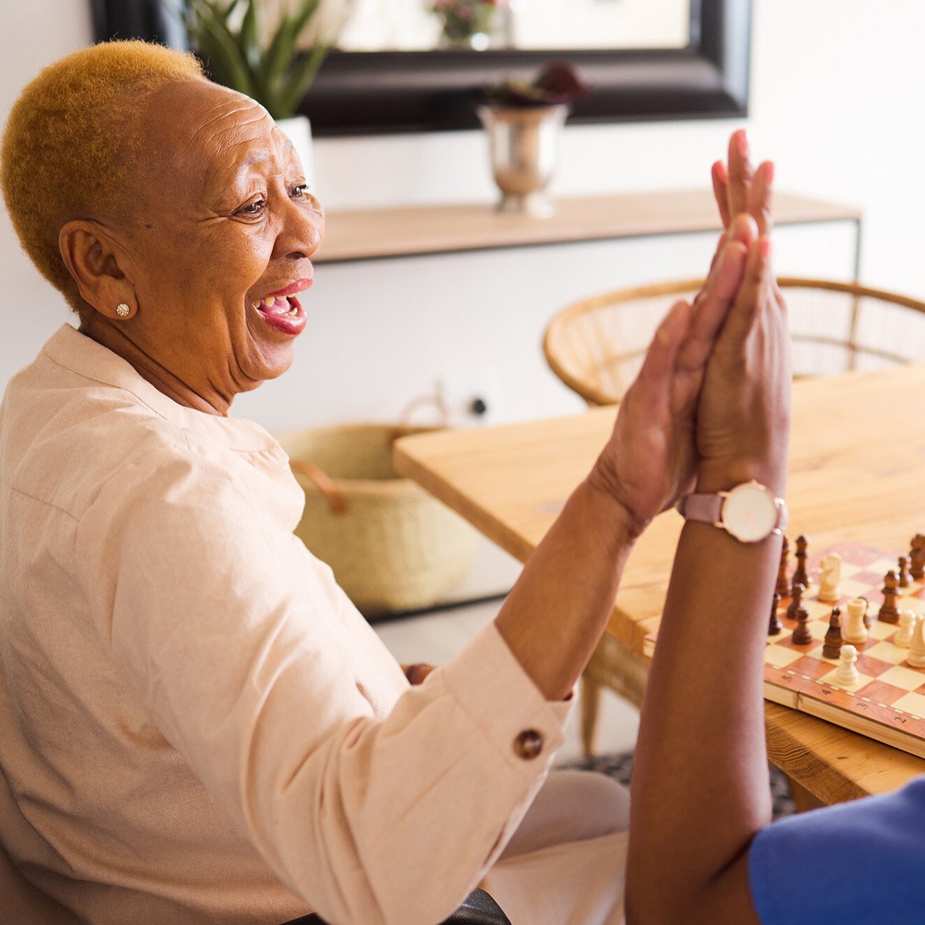 Senior woman playing a game and giving high five to caregiver