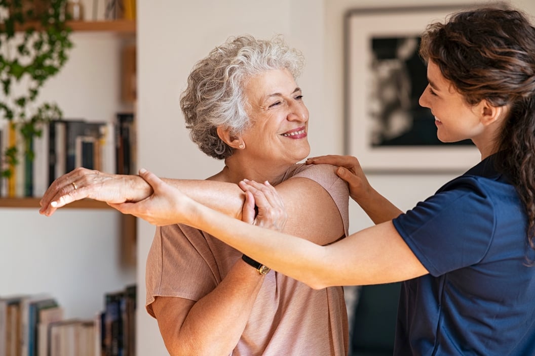 Senior woman stretching with a caregiver