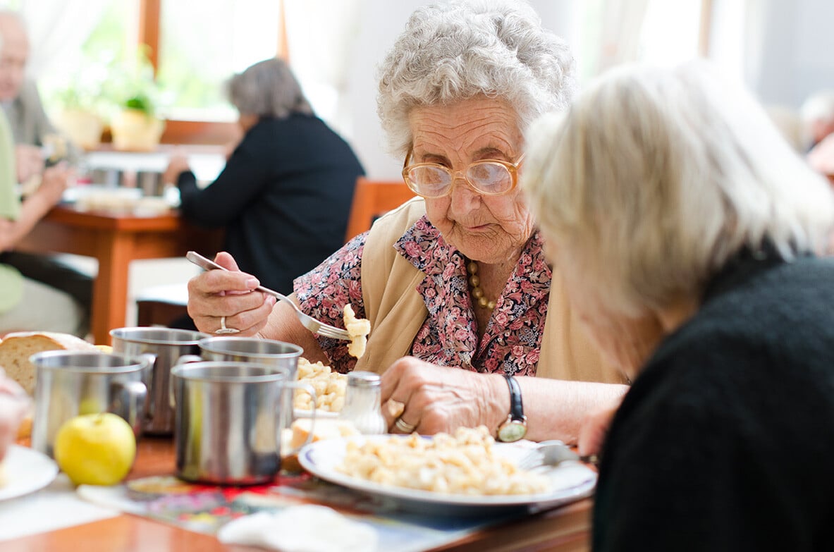 Elderly lady eating breakfast in assisted living community