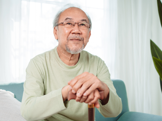 A senior living resident sitting on a couch holding a cane