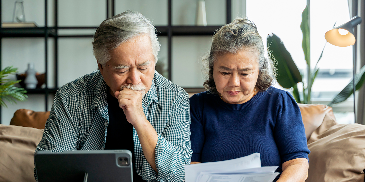 asian senior couple looking at billing statements calculating the costs of senior living