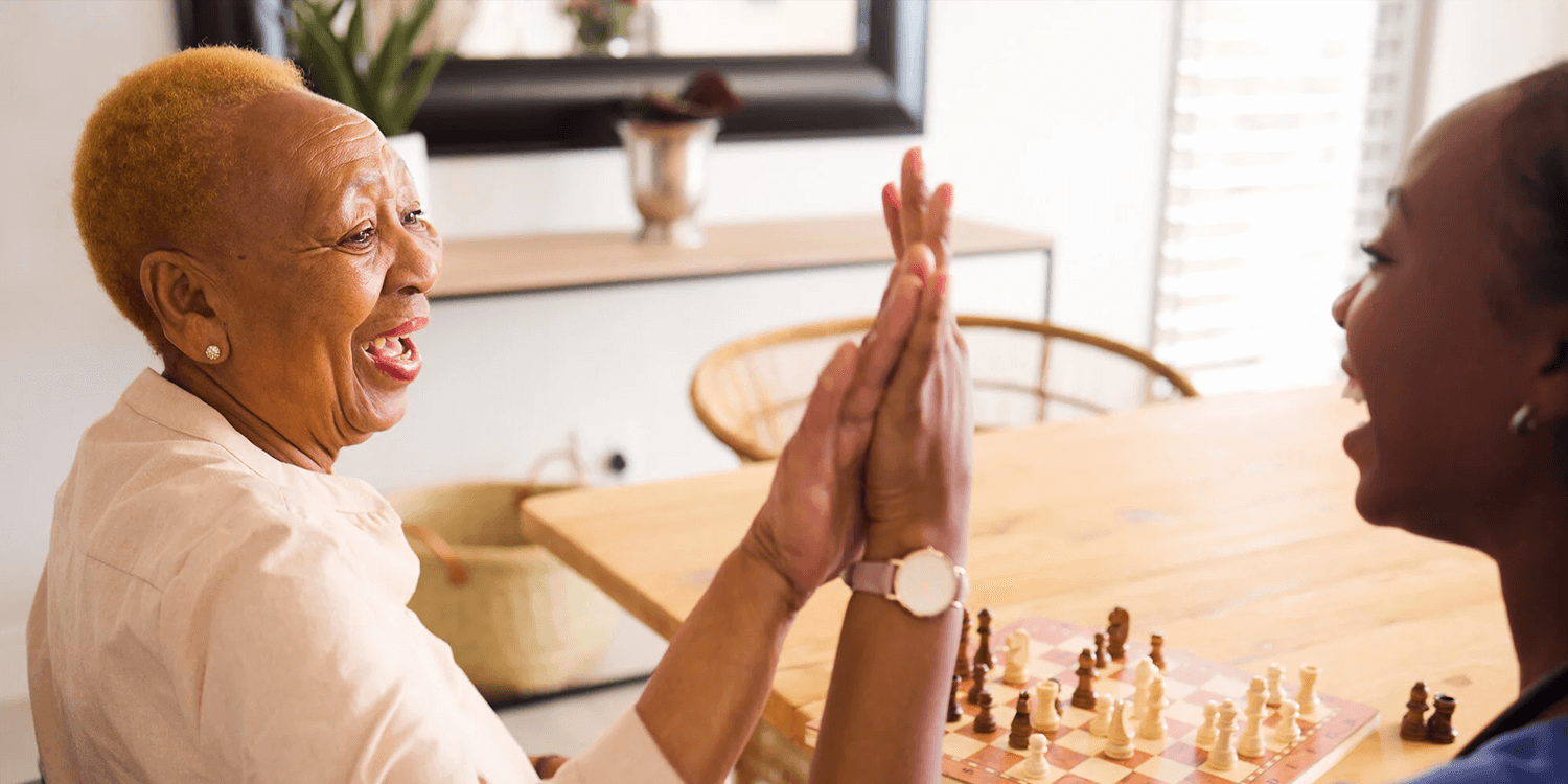  Senior woman playing a game and giving a high five to a caregiver