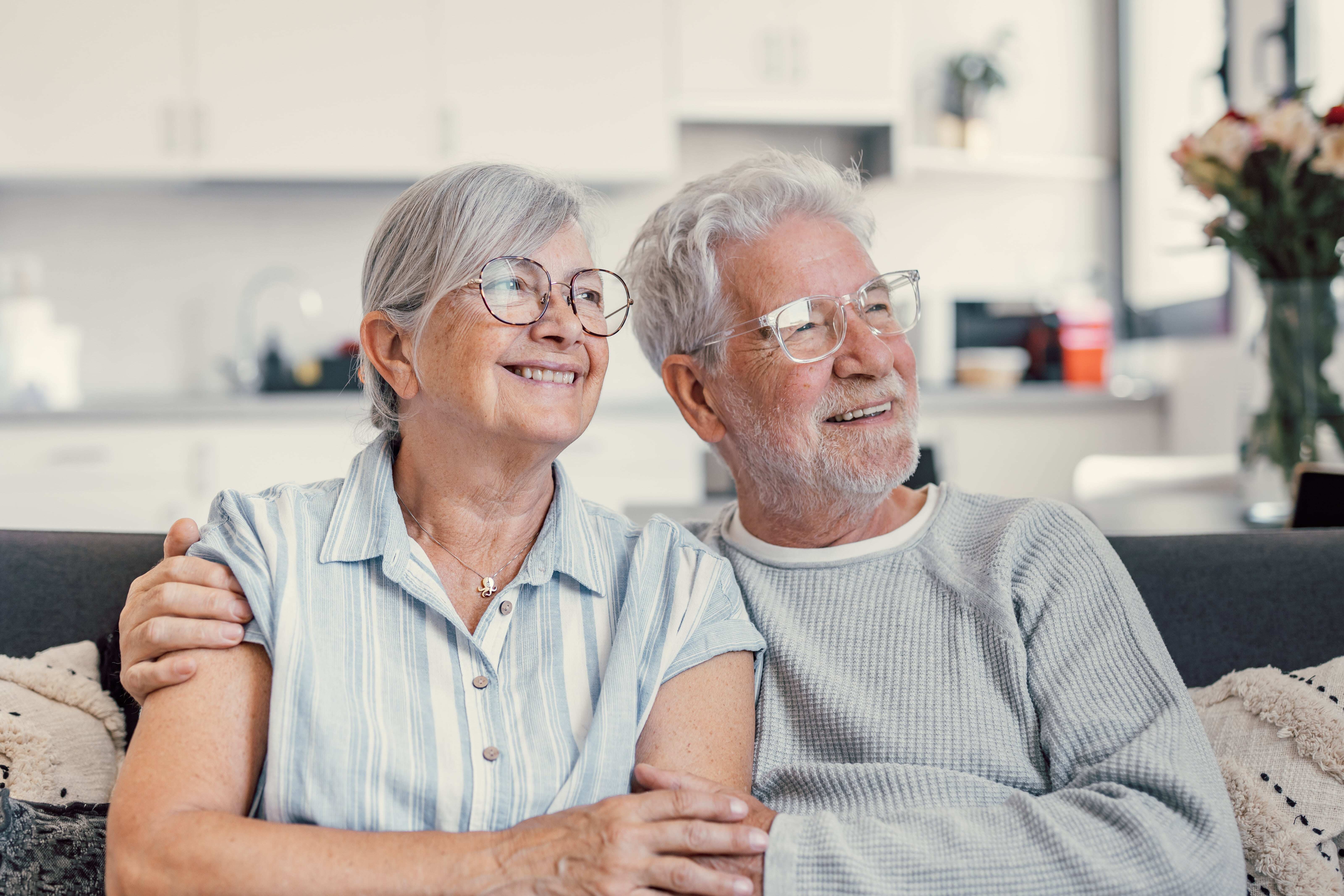 Senior couple enjoying peaceful moment relaxing together on cozy sofa in living room