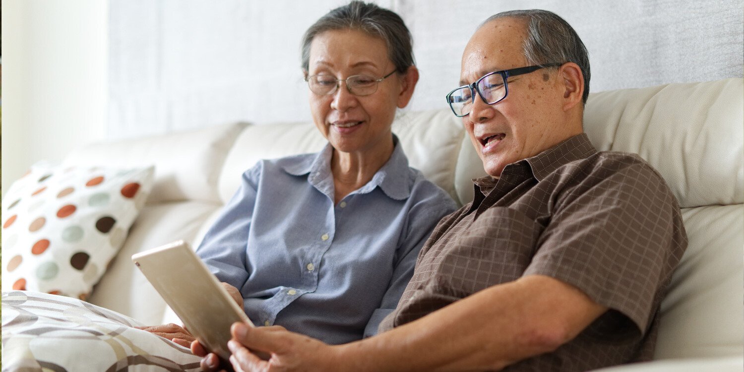 Senior couple sitting on sofa looking at tablet together